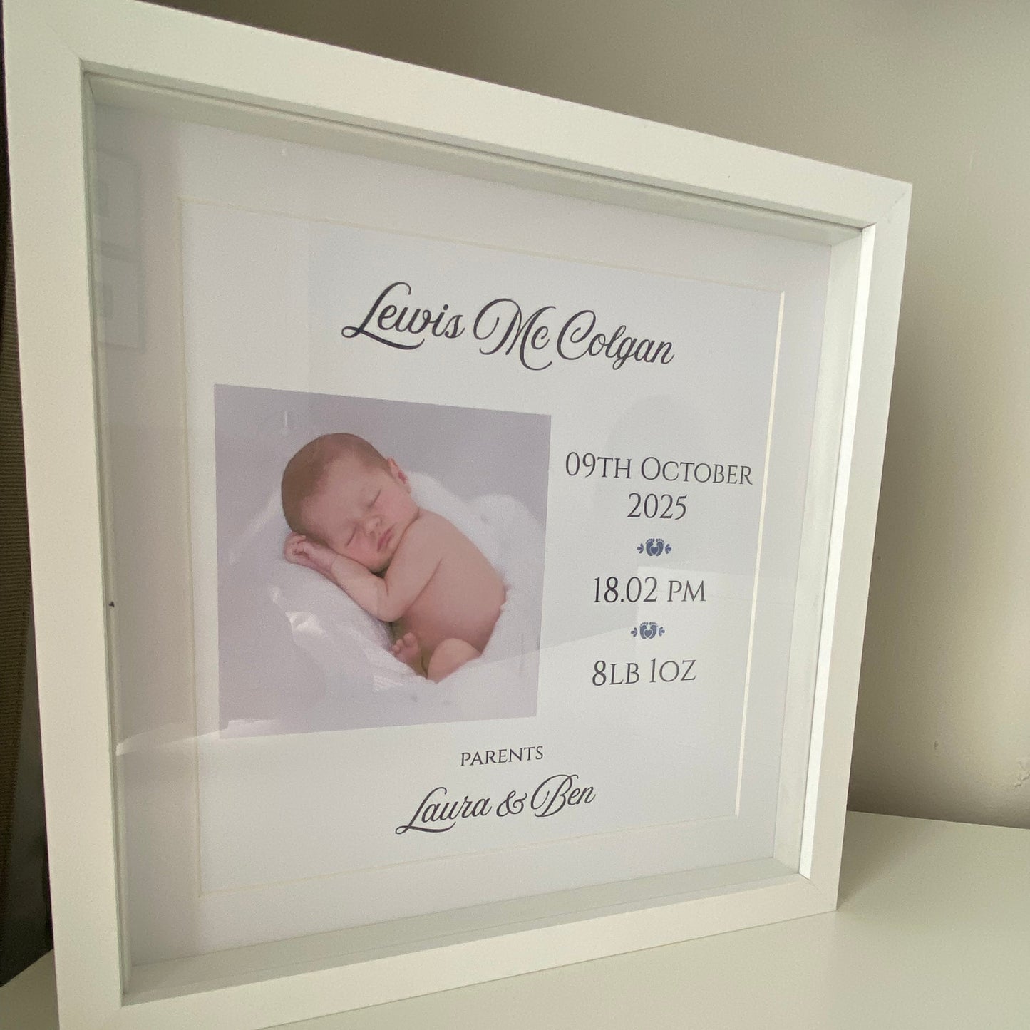 Framed picture of a newborn baby with personalized text on a white background