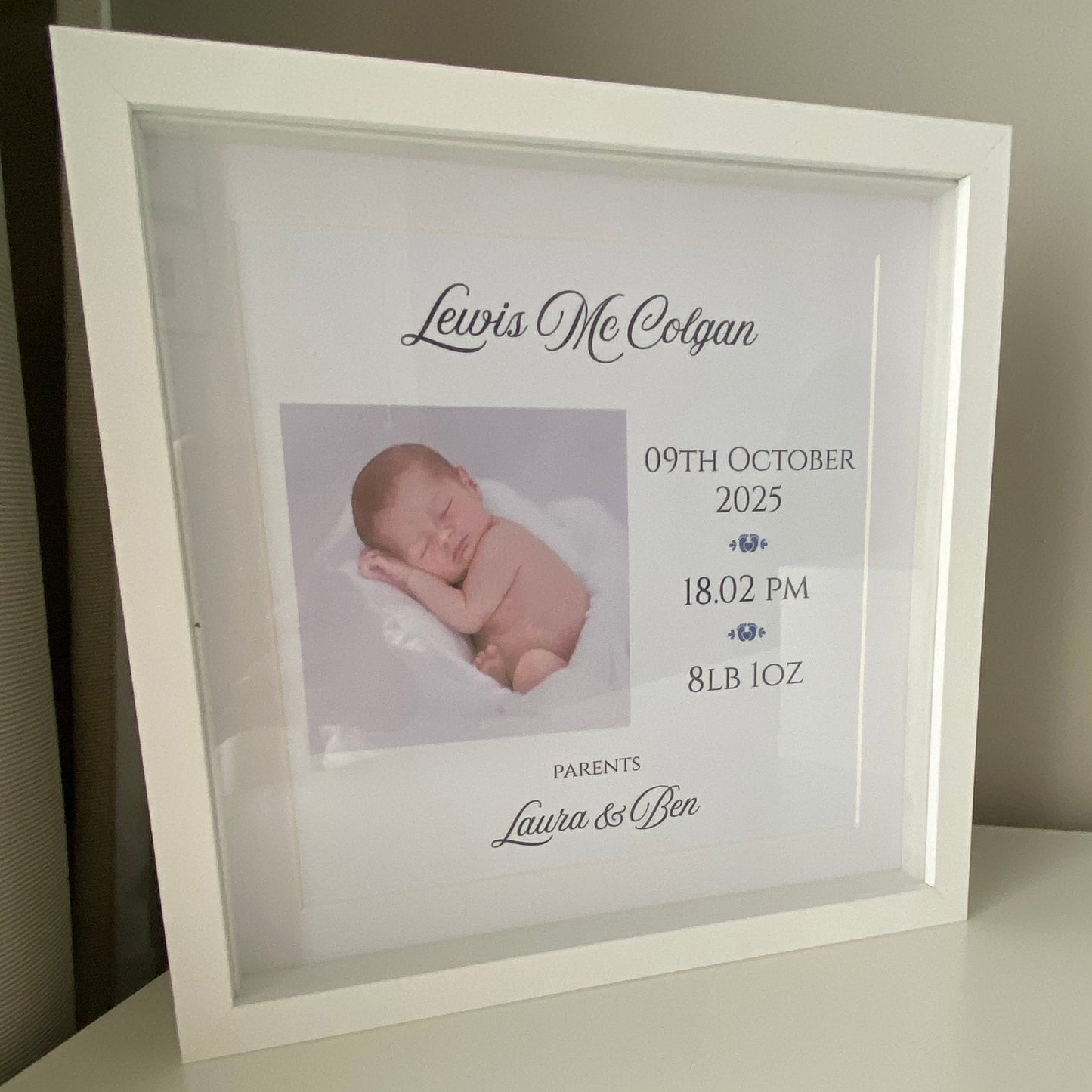 Framed photo of a newborn baby with birth details on a light background