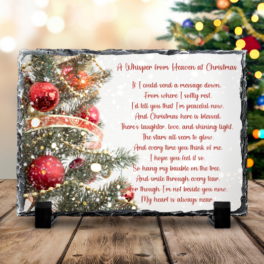 Decorative plaque with Christmas tree and poem on a wooden surface with blurred festive lights in the background.