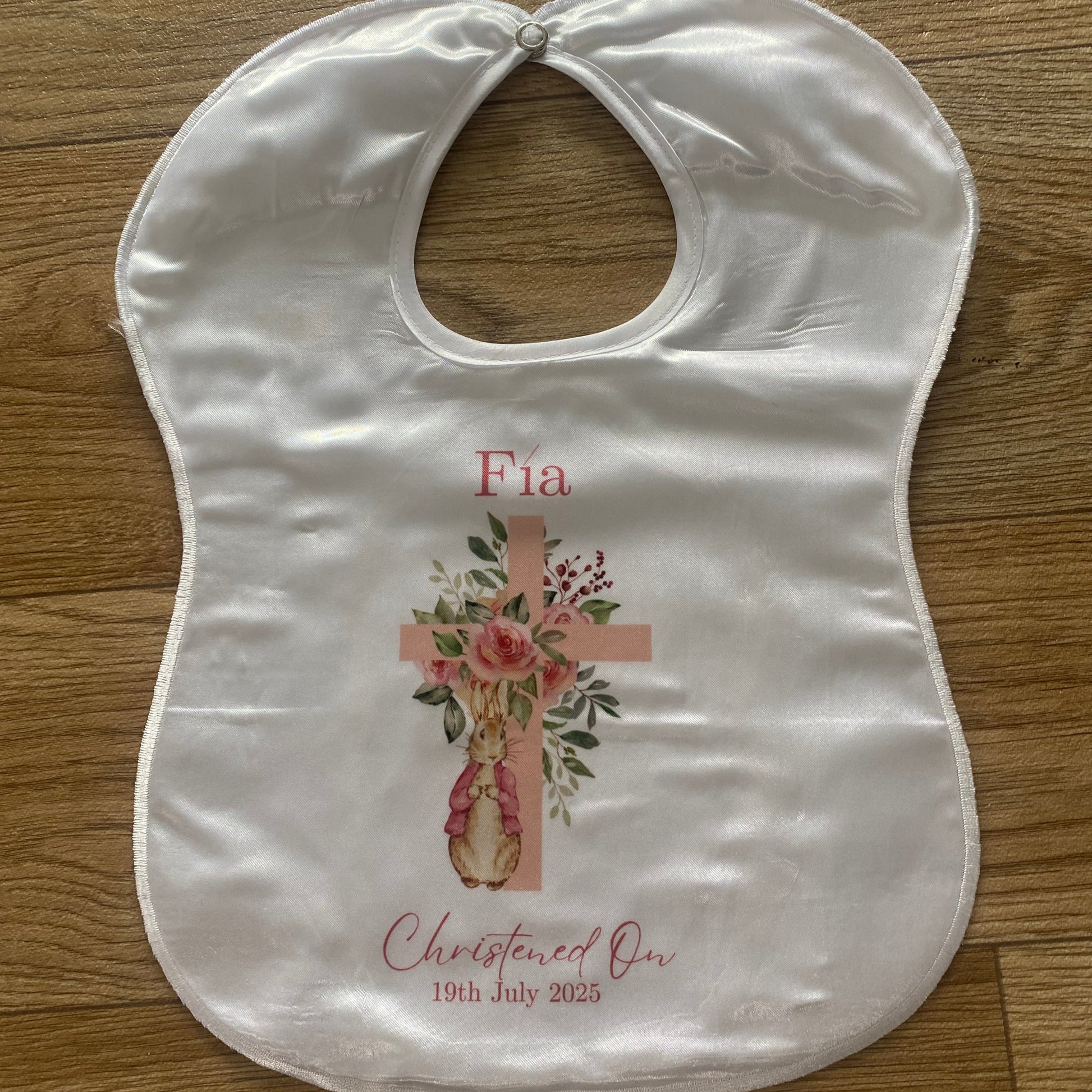 Baby bib with floral design and text on a wooden surface