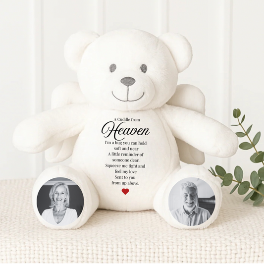 White teddy bear with photos of a couple on its paws, placed on a white surface with a light background.
